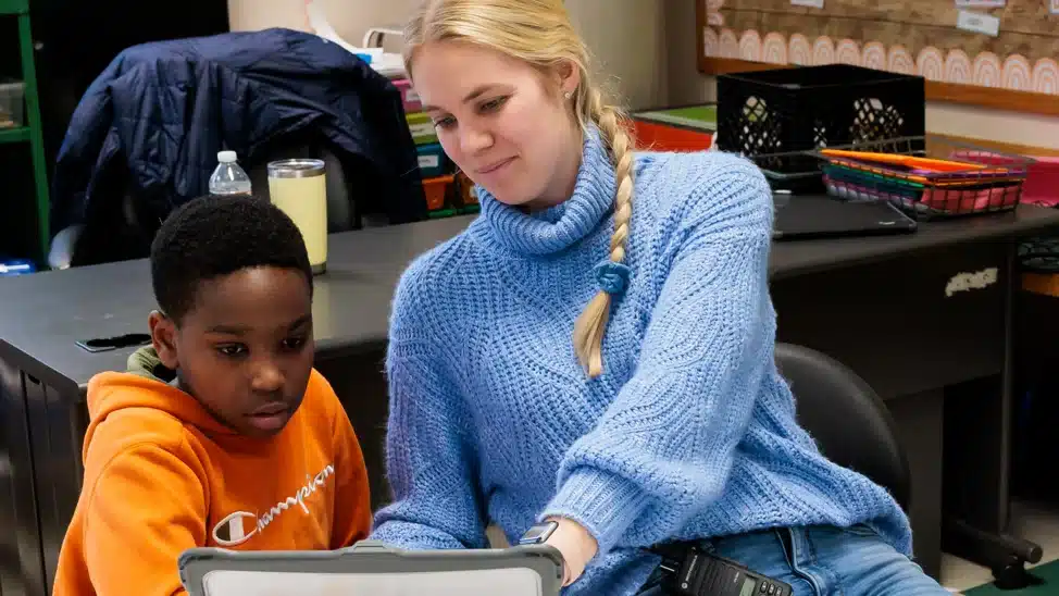 Teacher helping student on computer.